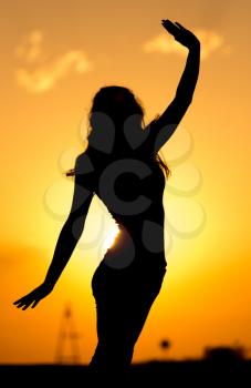 Silhouette of a beautiful girl at sunset .