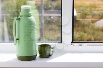 thermos with a glass on the window .