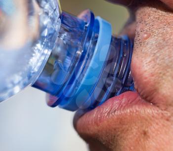 Man drinks water from a plastic bottle .