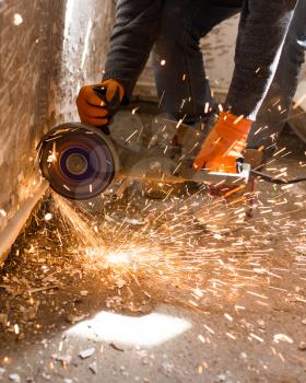 Worker cuts a metal pipe with sparks .