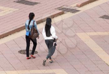 Two girl is walking along paving stones .