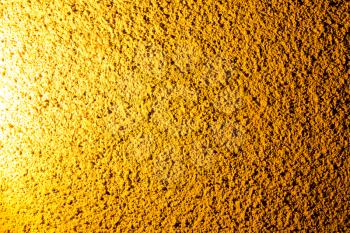 Plaster on a wall in gold lighting as a background .