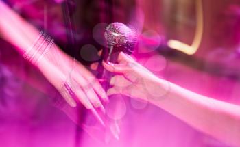 Microphone in the hands of the girl on stage .