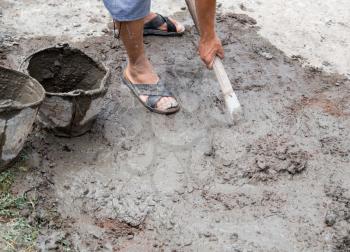 Worker mixes concrete with a shovel at the construction site