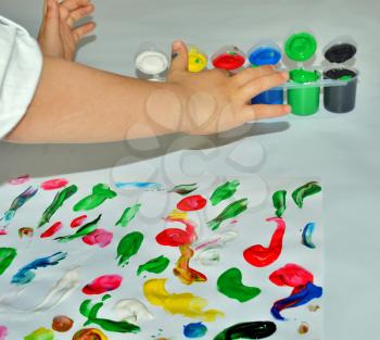 Kid paints with her fingers with different color paint