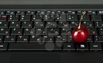 Royalty Free Photo of a Cherry on a Computer Keyboard