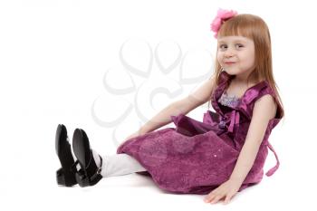Little beautiful girl sitting on the floor in the studio. Isolate on white