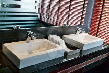 two square sink in the bathroom with a window and shutters