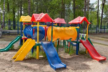 Plastic multi-colored children's playground in a pine park on a sunny day