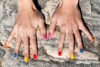 Two female hand with the fashionable color nail polish on the stone