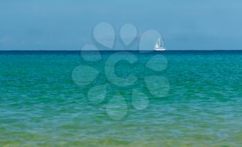 white sailboat on the azure sea on the horizon