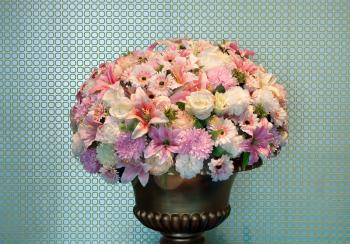 bouquet of flowers in a brass vase, textured walls in the background