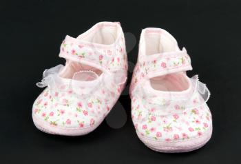 A pair of baby pink slippers on a black background