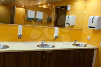 sink in a public toilet with yellow walls