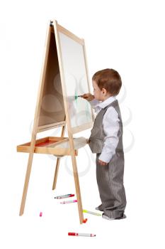 A child paints on an easel in the studio, isolate on white