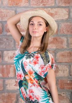 girl in a straw hat on a background of vintage brick wall
