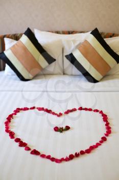 Heart of rose petals laid out on the bed, honeymoon
