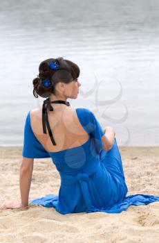 girl in a blue dress sitting on the beach