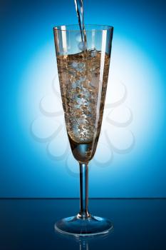 Champagne poured into a glass. Blue background
