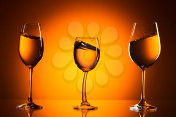 Three glasses on orange background with the liquid. On the background of orange light spot.