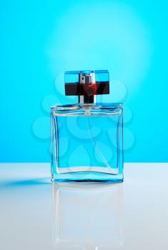 Perfume on blue background with reflection