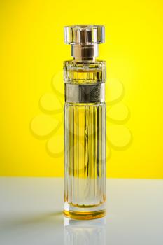 Cylindrical perfume bottle on a yellow gradient background.