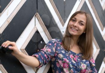 Portrait of a happy young girl who relies on the wooden wall