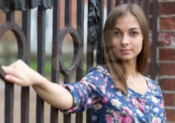 Portrait of a beautiful girl near the old rusty wrought fence.