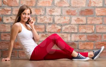 girl casual design with the phone sitting on a brick wall