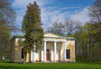 Old house with columns in the woods on a background of blue sky with clouds