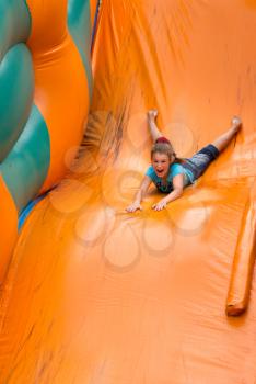 Excited, cute little girl sliding on a inflatable slide.