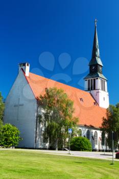 A white rural church stands against a cloudy blue sky.