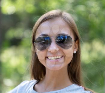 portrait of a girl in sunglasses in the forest close up