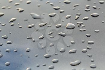 drops on a gray mirror surface which reflects the sky