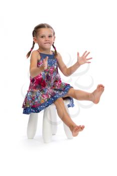 Little girl in a colored dress on a chair in the studio, isolate on white.