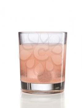 Orange effervescent tablet in a glass of water. Isolate on white.