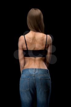 Girl in jeans with naked back relief. Isolate on black.