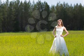 young girl in a wedding dress smiling in the field.