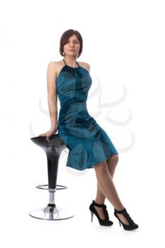 Beauty woman on a bar chair in a blue dress in the studio, isolate on white.