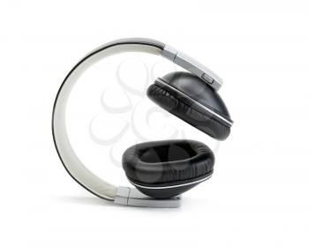 Black leather headphones lie sideways on a white background in the studio. Isolate.