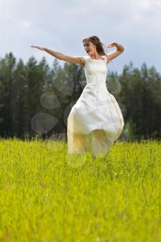 Girl in a wedding dress jumping in a field