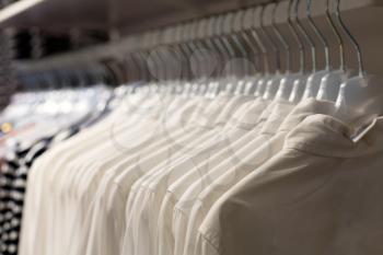 White Fashionable clothes on hangers in store