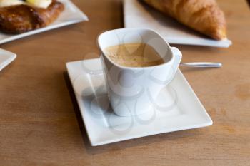 Still life. A cup of coffee and a croissant. On a wooden table.