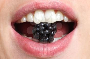 Royalty Free Photo of a Person Eating a Blackberry