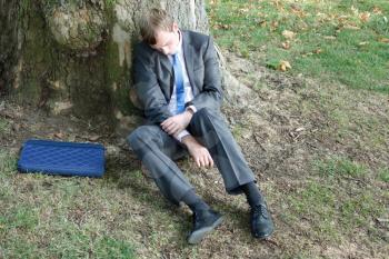 Royalty Free Photo of a Businessman Sleeping by a Tree