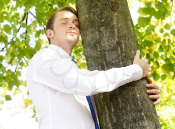 Royalty Free Photo of a Businessman Hugging a Tree