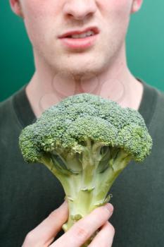 Royalty Free Photo of a Man Grimacing at Broccoli