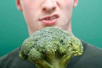 Royalty Free Photo of a Man Grimacing at Broccoli