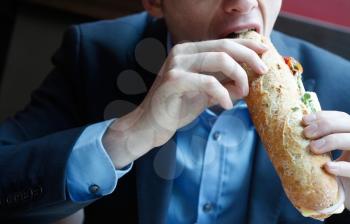 Royalty Free Photo of a Businessman Eating a Sub