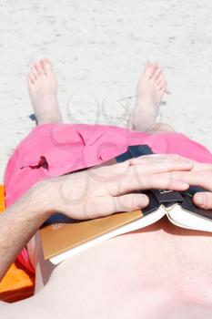 Royalty Free Photo of a Man Reading a Book at the Beach